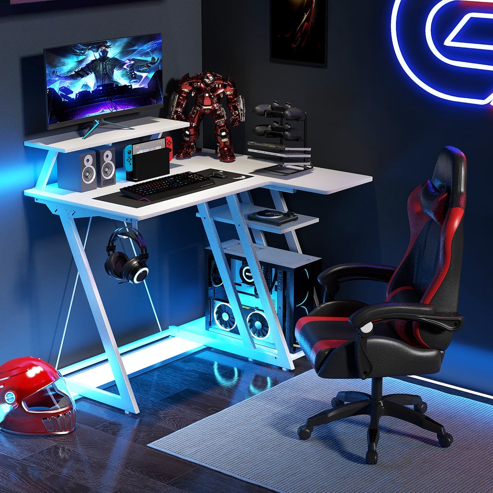 The gaming desk set up with computer, monitors and gaming chair in a dark room