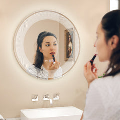 The illuminated mirror reflecting a woman applying lipstick in a bright modern bathroom
