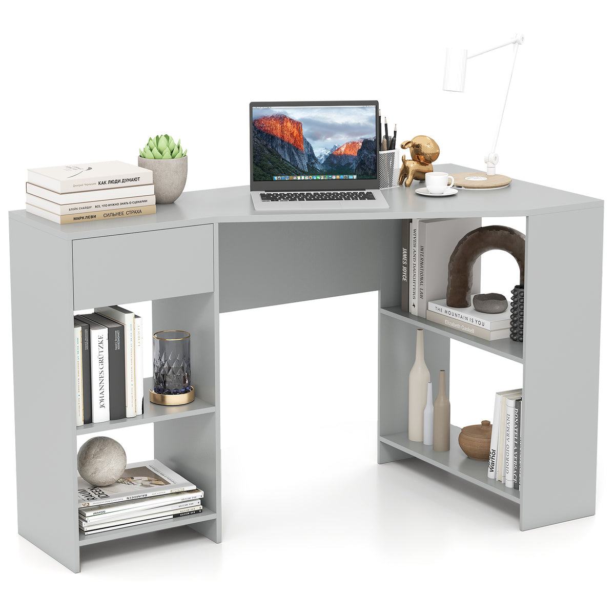 Grey L-shaped computer desk with open shelves and a drawer, laptop on top