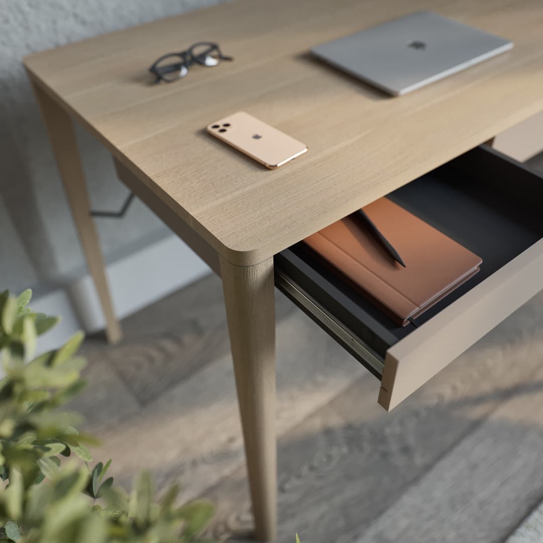 The workspace desk showing a close up of the open drawer with a notebook and pen inside