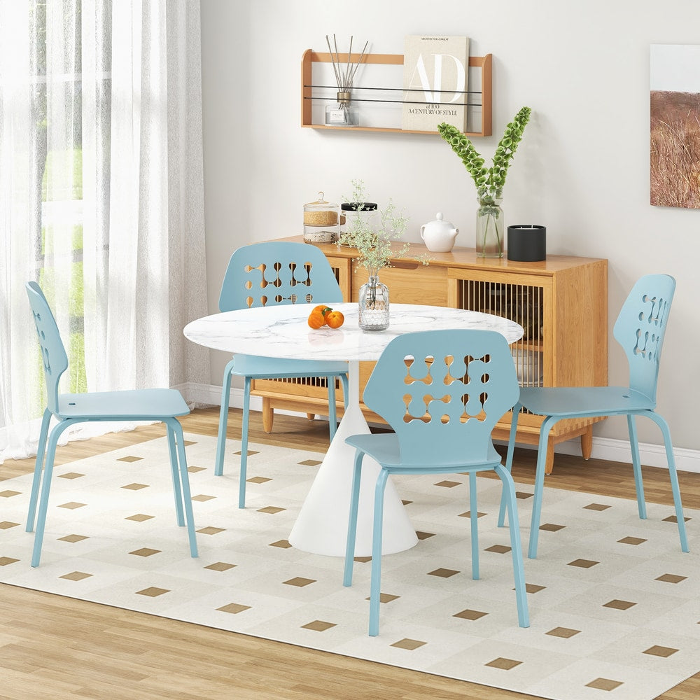 Four blue metal dining chairs placed around a white dining table in a bright room