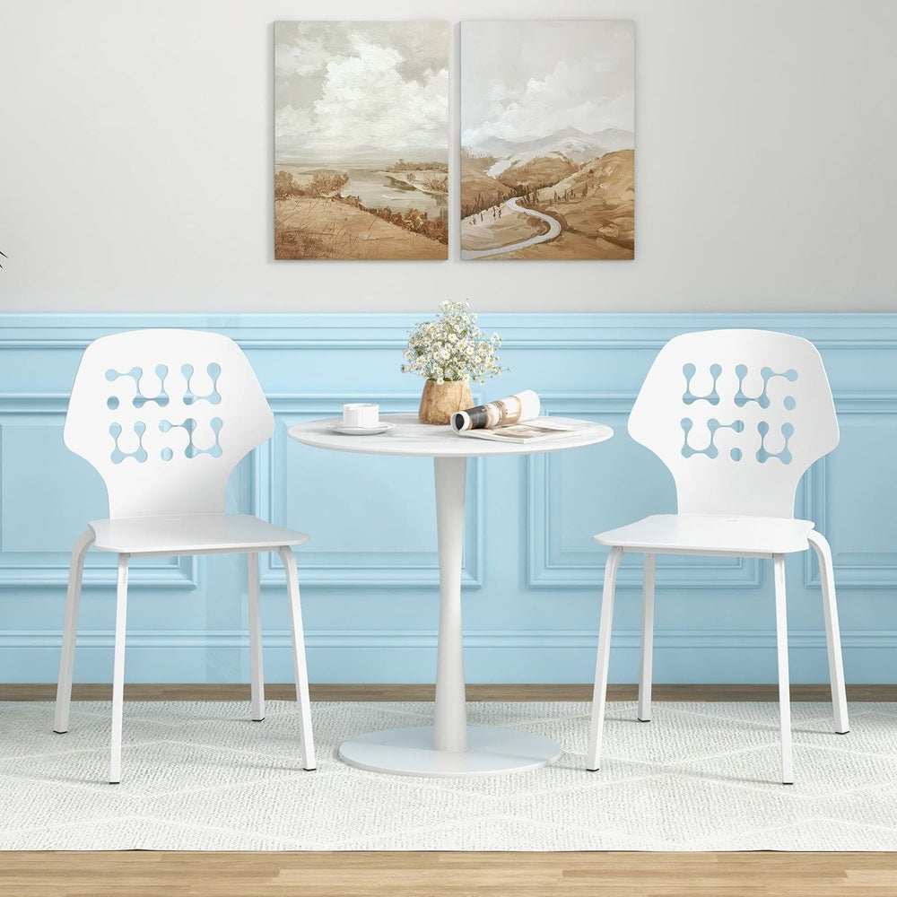 Two white metal dining chairs with hollowed backrests next to a table