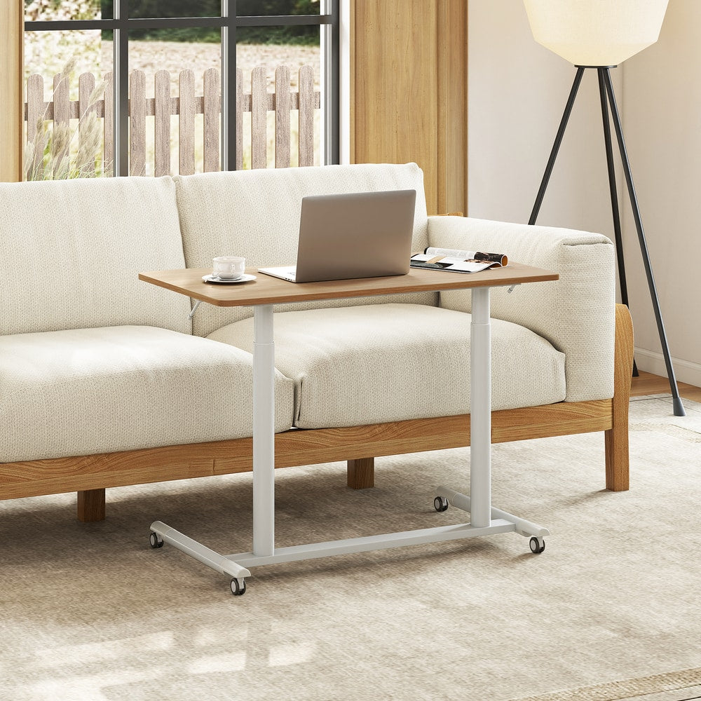 The mobile standing desk next to a sofa with a laptop on top
