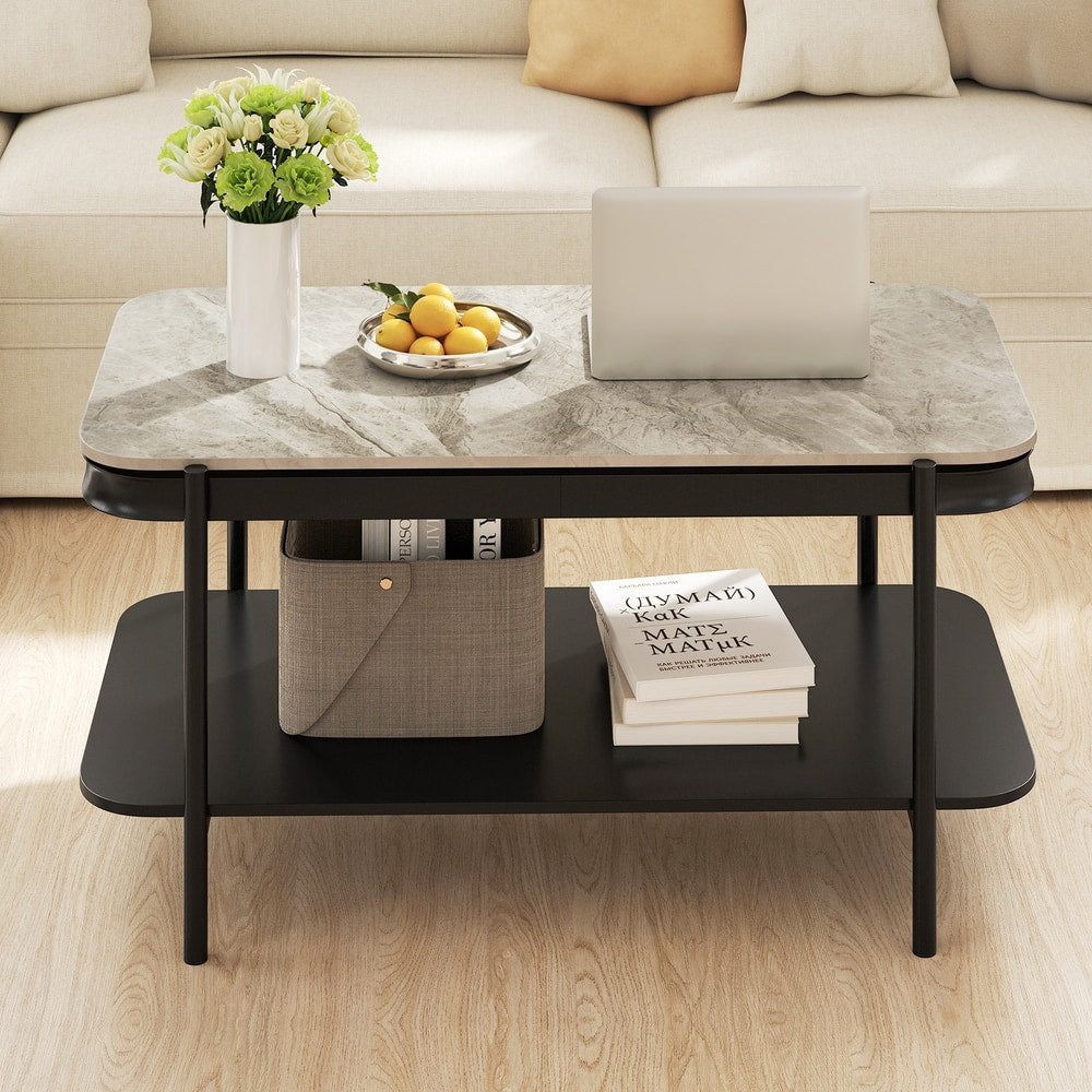 Grey marble effect coffee table with a laptop and fruit bowl on top, in a living room