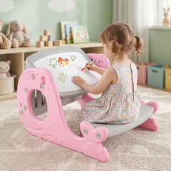 A young girl draws on the whiteboard of the pink kids table and chair set