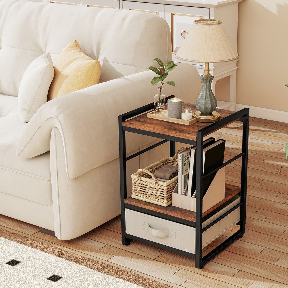 The bedside table holding a lamp and books next to a sofa with a fabric drawer at the base