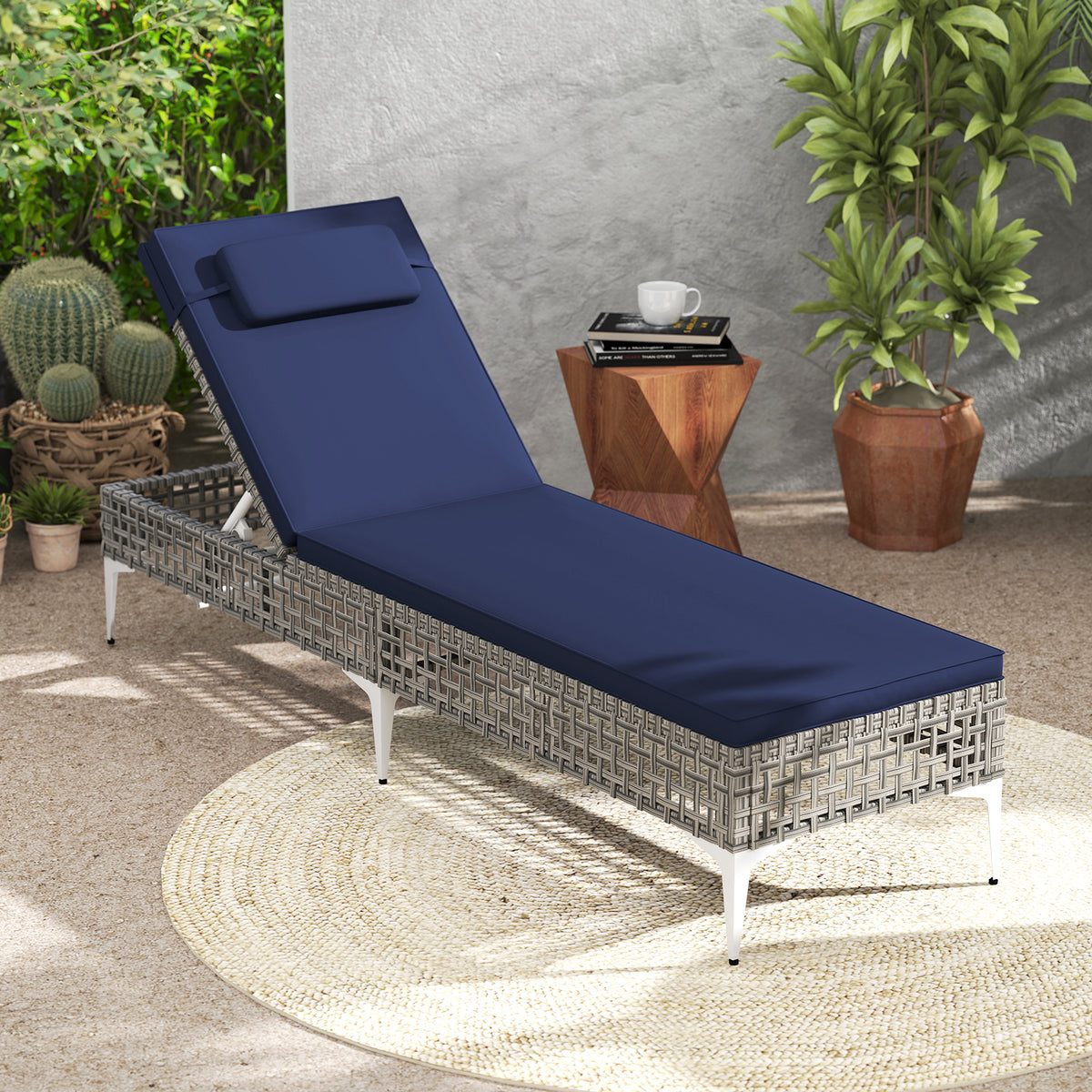 The outdoor chaise lounge with navy cushions is set up on a patio next to some plants