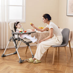 The beige high chair is shown in use with a mother feeding her baby at a dining table