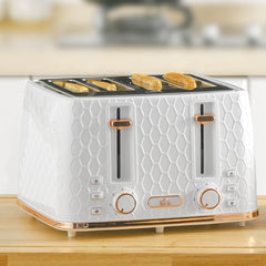 Four slices of toast cooking in the white honeycomb toaster on a wooden counter