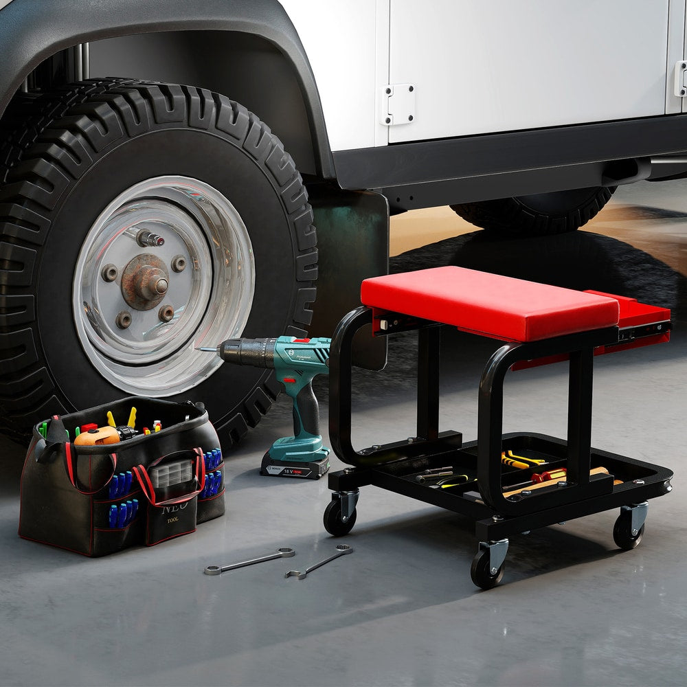 The garage creeper seat next to a car wheel with a toolbox and tools on the floor
