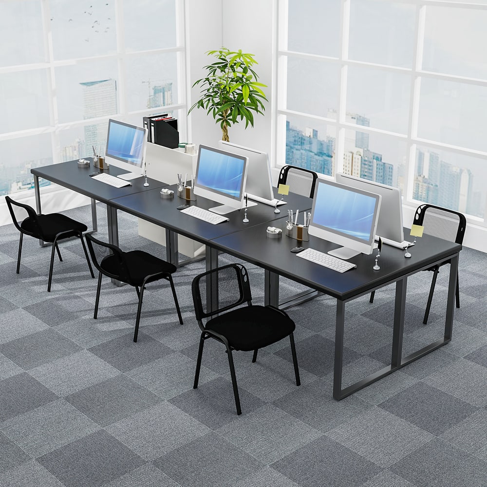 The office chairs positioned at a long desk with computers in a bright open plan office