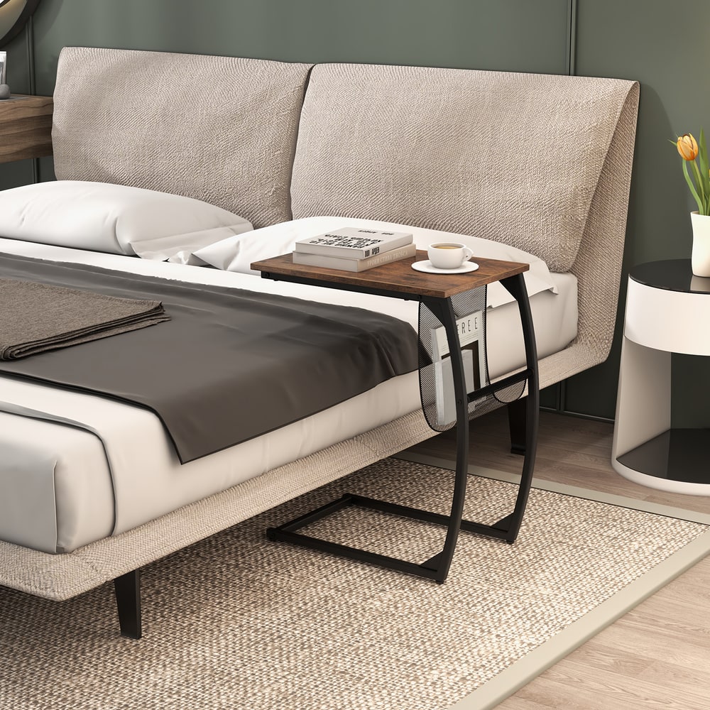 Compact sofa side snack table next to a bed with a book and cup on top