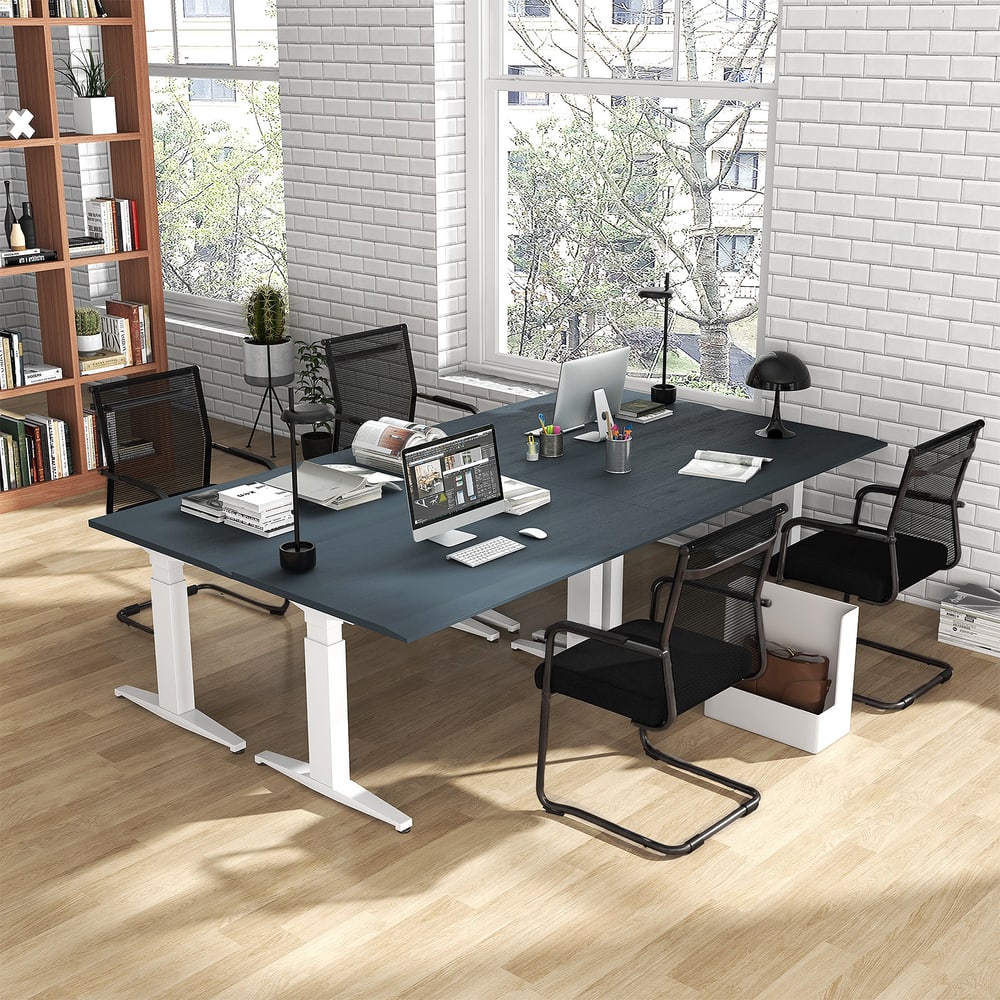 The office chairs placed around a large dark desk in a home office with a brick wall