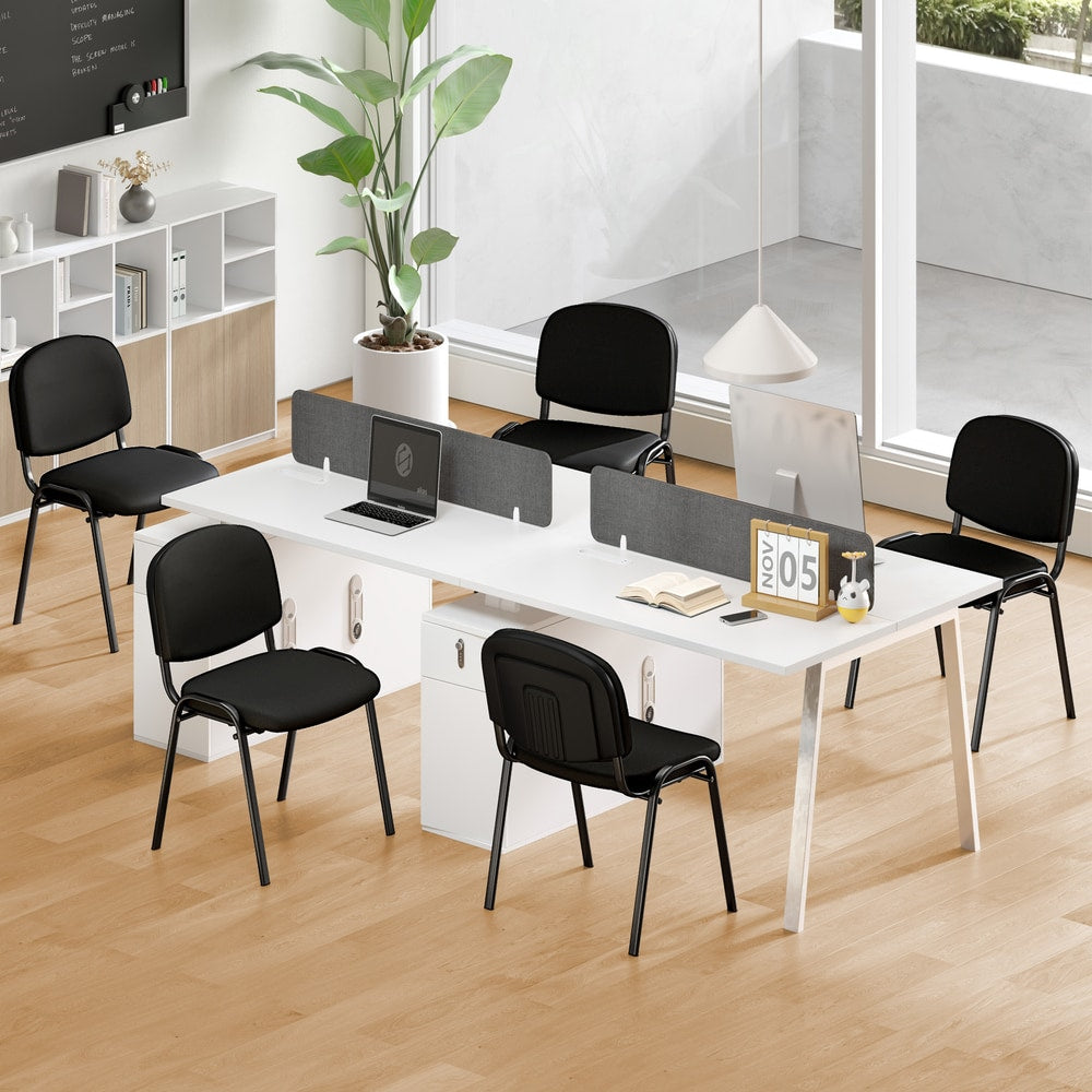 The office chairs placed around a white desk in a modern bright workspace with wooden flooring