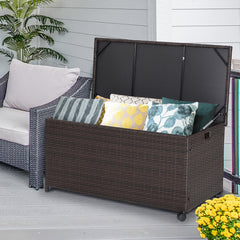 The patio rattan storage container shown on a deck with outdoor furniture and cushions inside