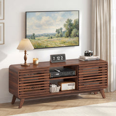 The entertainment center in a living room with a lamp, candle, and electronics on top
