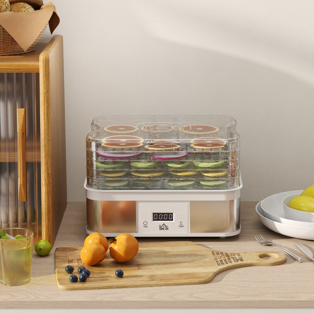 The food dehydrator on a kitchen counter, surrounded by fresh fruit and a drink