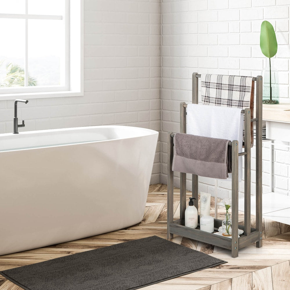 The grey wooden towel rack with three bars and a shelf is shown in a bathroom setting next to a bathtub