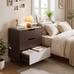 The wooden nightstand with one drawer open showing folded clothes, in a bedroom setting
