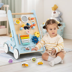 A baby girl playing with the blue baby walker in a room