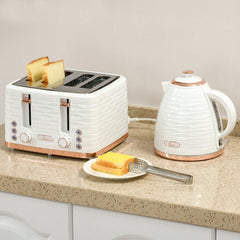 The four-slice toaster with bread slices inside sitting on a kitchen counter next to a kettle