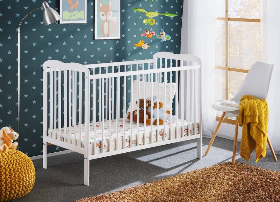 Ala Cot Bed in white, a baby cot bed with mattress and bedding in a nursery room
