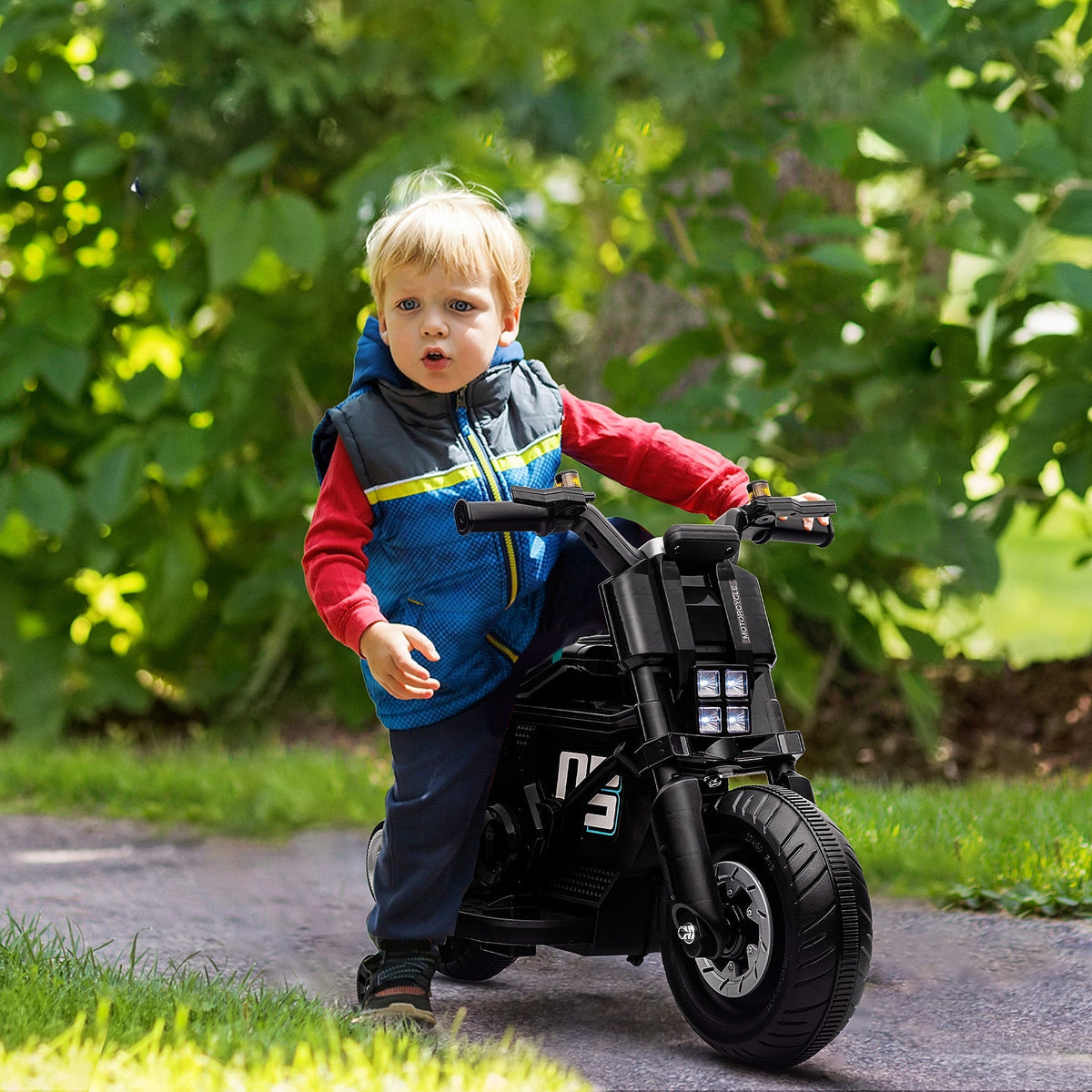 A young boy riding the black kids electric motorbike on a path outdoors
