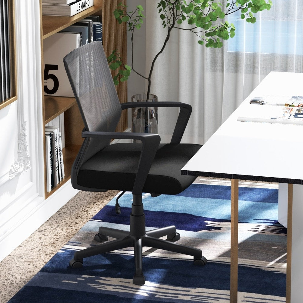 Black ergonomic desk chair in a home office setting next to a white desk