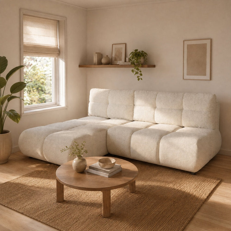 Corner Sofa Bed Milo in a light cream fabric, shown in a living room setting with a coffee table