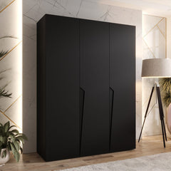 The hinged wardrobe in a sleek black finish, displayed in a contemporary room with a floor lamp