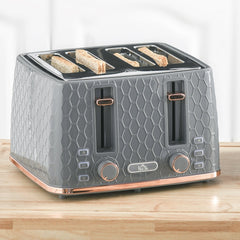 The grey four-slice toaster with four slices of toast in the slots, on a wooden surface