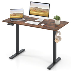 The computer desk with a laptop, keyboard, mouse and headphones hanging on the side