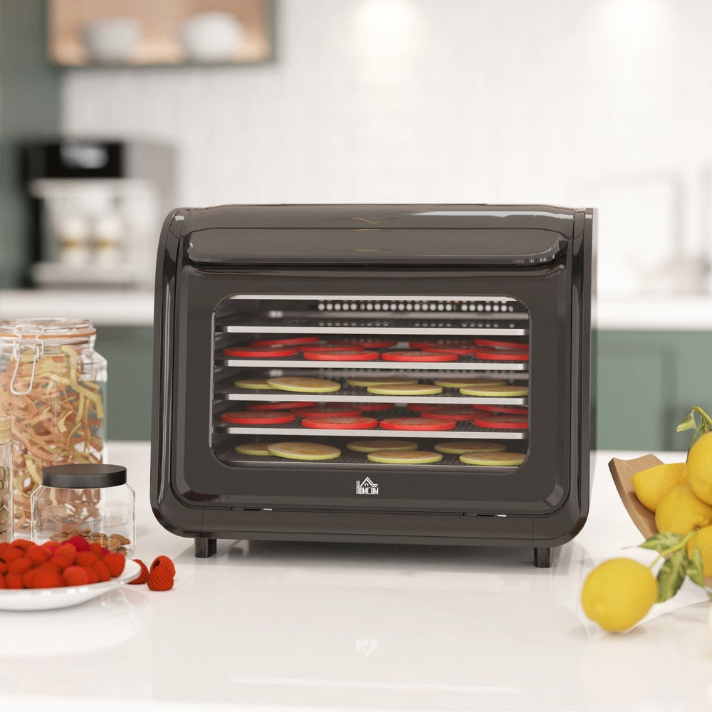 Black six-tray food dehydrator on a kitchen counter with fruit and jars