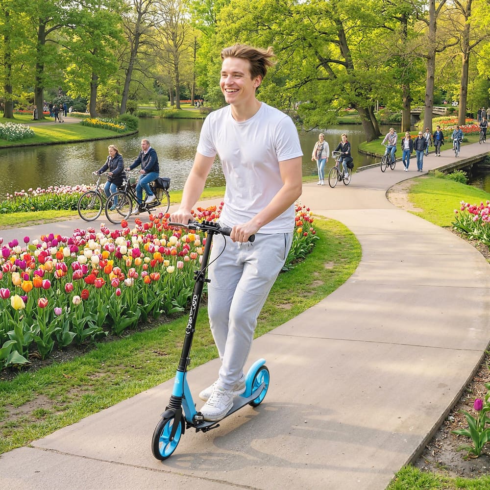 The blue kick scooter being ridden by a smiling man along a park path lined with tulips