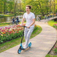 The blue kick scooter being ridden by a smiling man along a park path lined with tulips