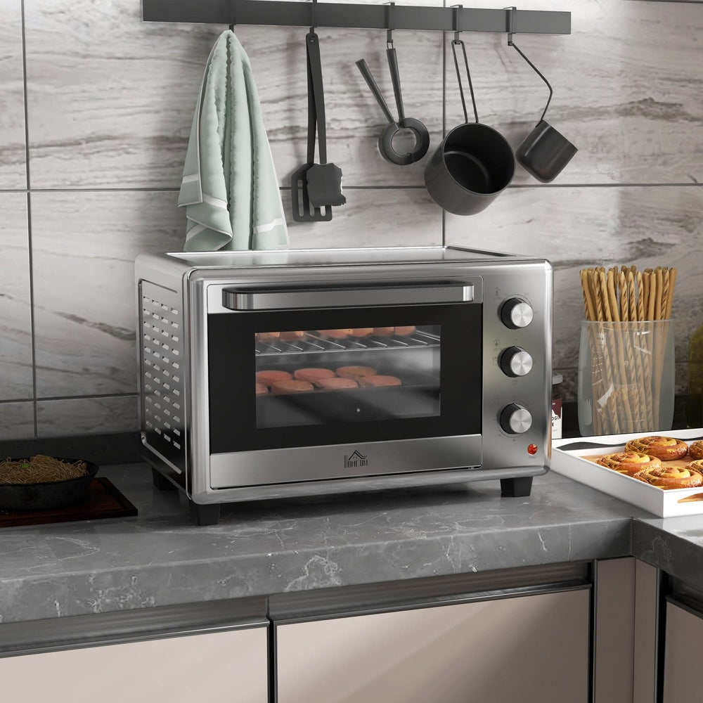 The silver electric oven placed on a kitchen counter with a glass door and three control dials