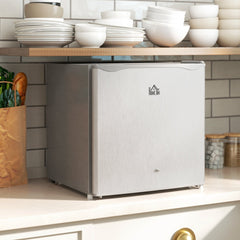 The grey countertop fridge is shown on a kitchen counter with shelves above