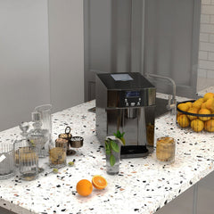 The ice maker machine sitting on a kitchen counter surrounded by glasses and fresh fruit