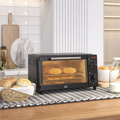 The black mini oven on a kitchen counter with bread in a basket and a jug of milk nearby