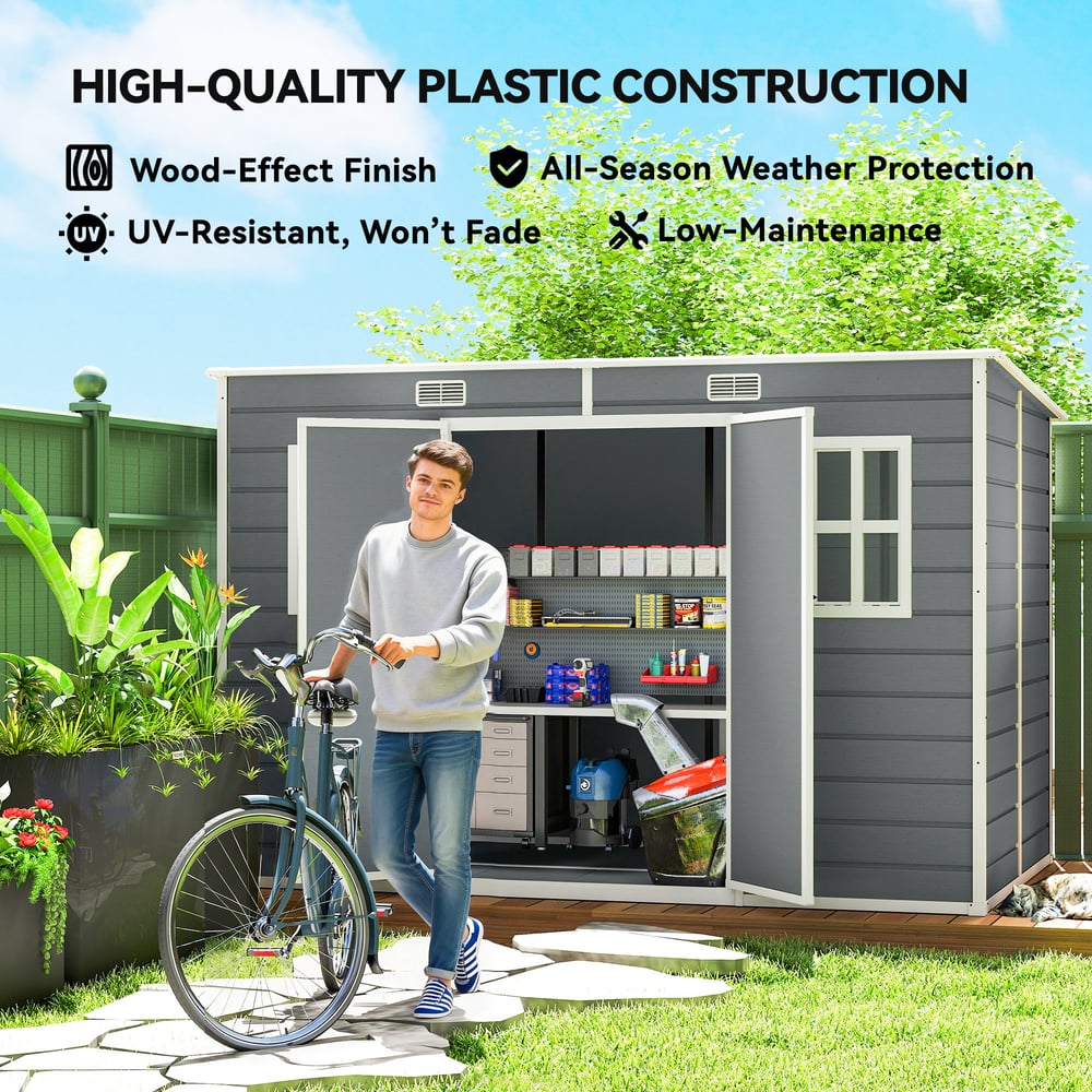 A man with a bicycle stands by the grey garden shed, which is in a garden setting