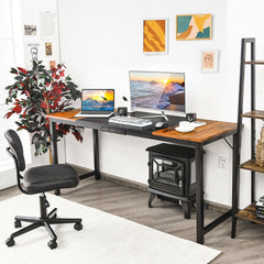 The office desk set up in a home office with a chair, plant and wood burning stove