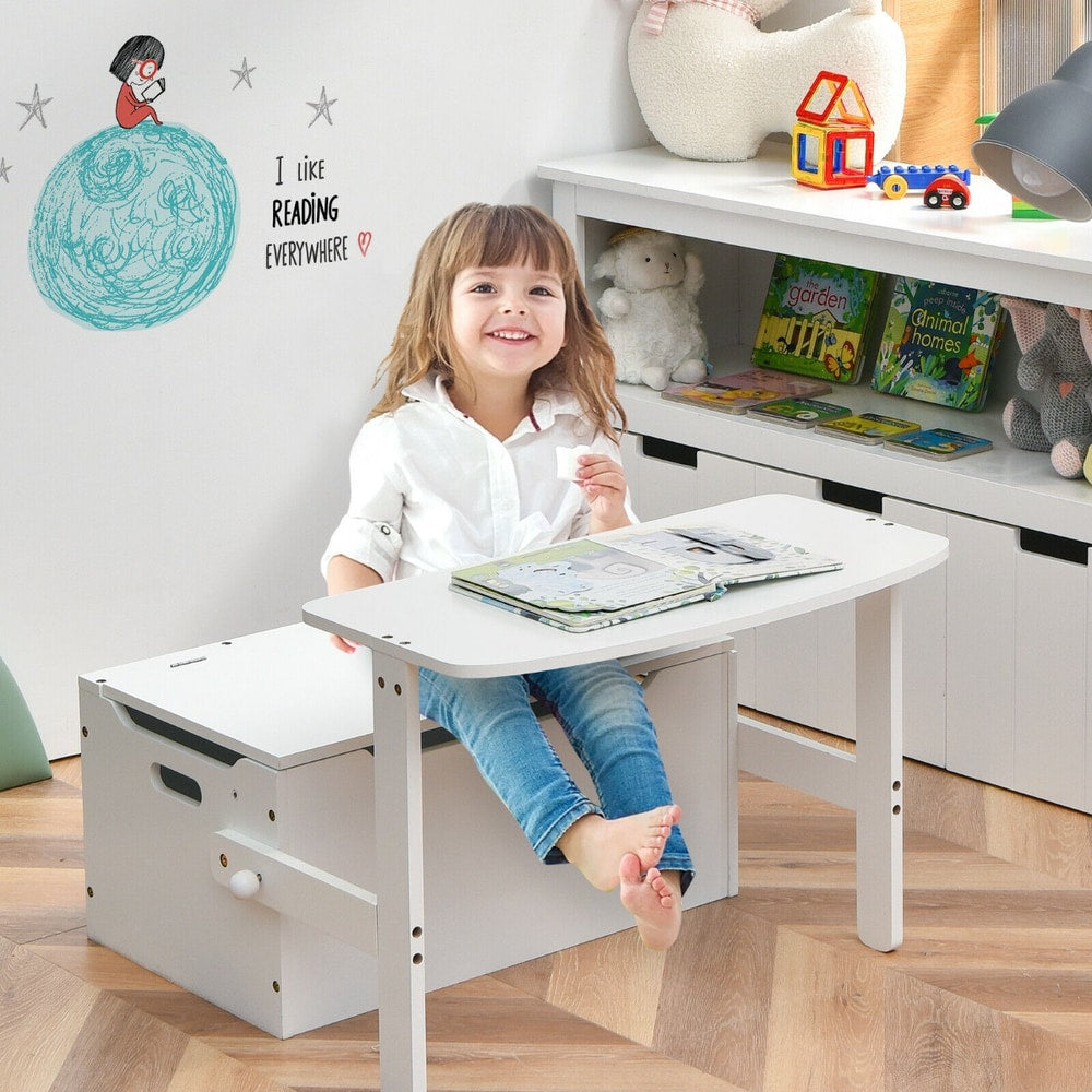 A happy young child sitting at the kids table and chair set, reading a book