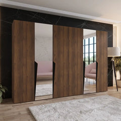 The hinged wardrobe in a dark wood finish with mirrors in a furnished room