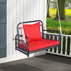Red cushioned porch swing chair hanging from a white railing on a wooden porch