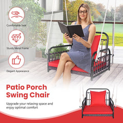 A woman reads a book while sitting on a red cushioned hanging porch swing chair