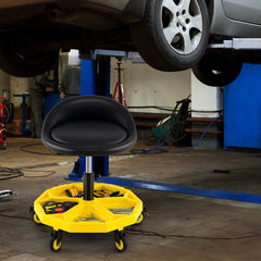 The rolling garage stool is shown under a car in a workshop setting