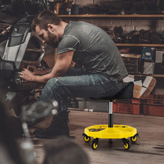 A man works on a motorcycle while sitting on the rolling garage stool