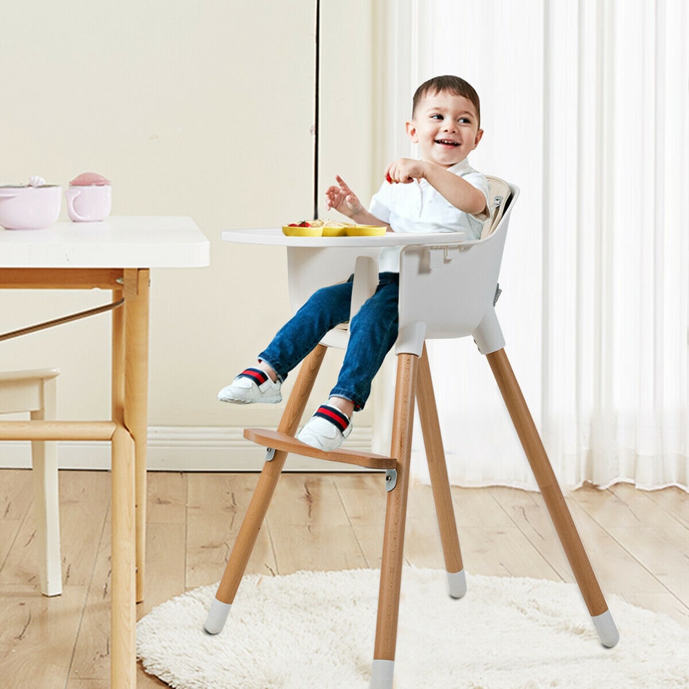 The wooden high chair with a white tray and padded seat standing on a rug