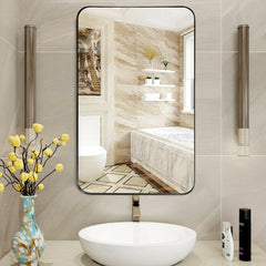 A black framed bathroom mirror with rounded corners is reflected in a sink in a bathroom setting