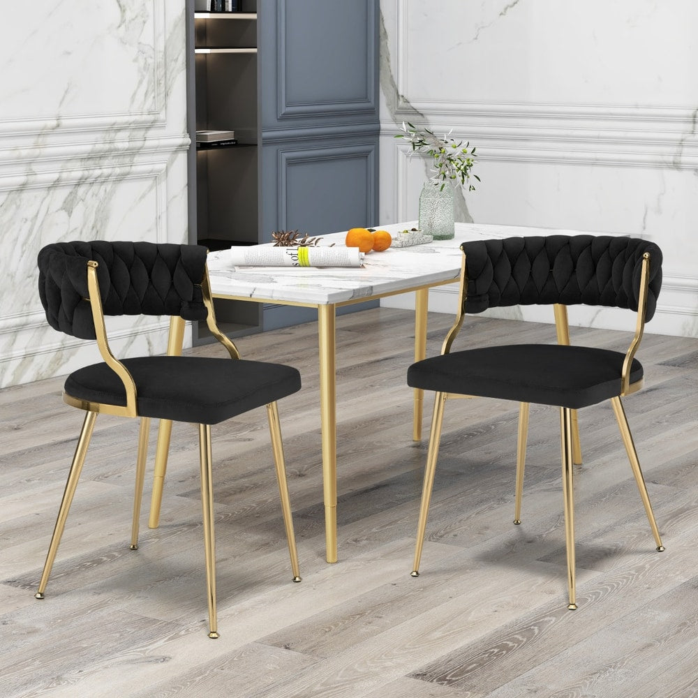 Two black velvet dining chairs with gold metal legs positioned at a dining table